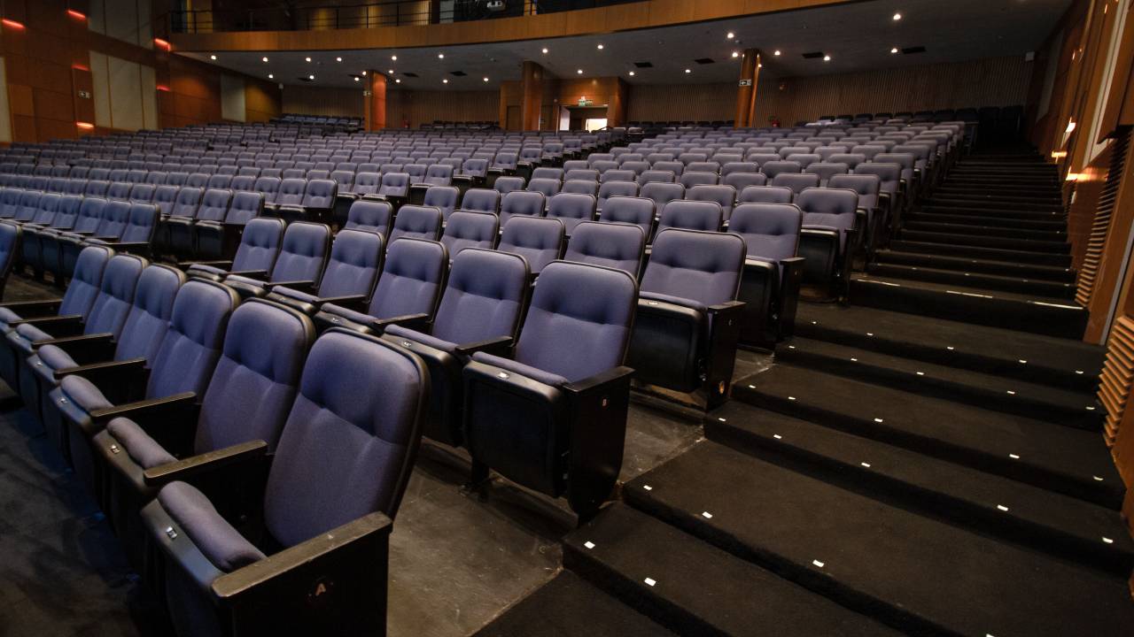 Imagem mostra plateia com poltronas azuis