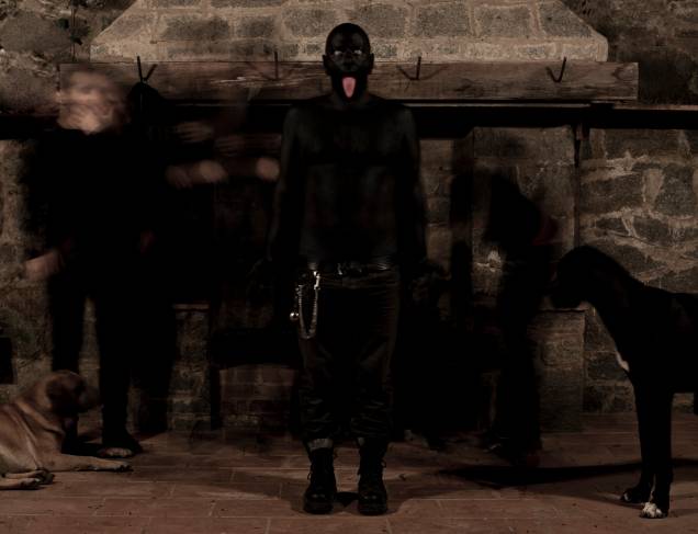 Sem título, 2012, do coletivo Cão, Brasil: performance cria uma paisagem negra, com sons distorcidos que trazem influência do rock industrial e de música eletrônica. O ambiente é construído com fumaça, luzes e projeção de imagens Sem título, 2012, do coletivo Cão, Brasil: performance cria uma paisagem negra, com sons distorcidos que trazem influência do rock industrial e de música eletrônica. O ambiente é construído com fumaça, luzes e projeção de imagens