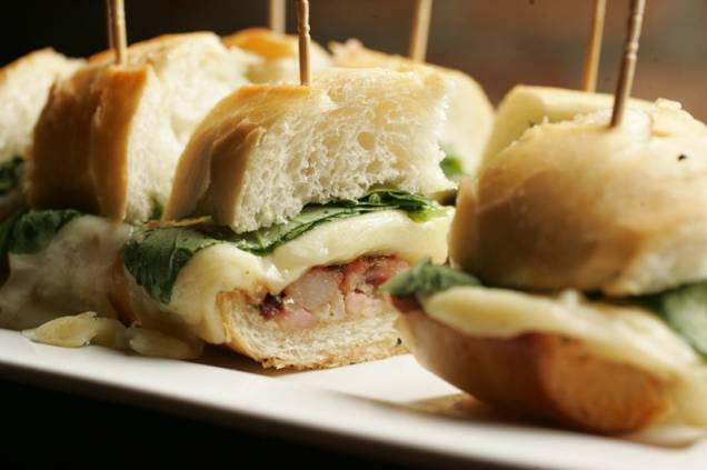 Cortado em seis pedaços, o sanduíche de linguiça, agrião e queijo provolone Cortado em seis pedaços, o sanduíche de linguiça, agrião e queijo provolone
