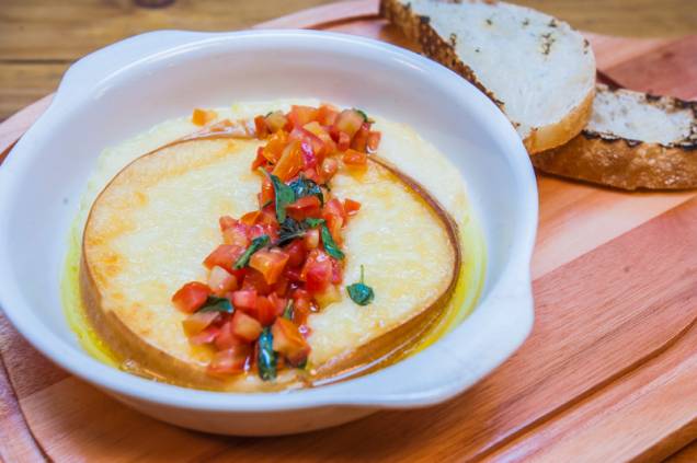 O provolone assado é acompanhado por cubos de tomate e molho de manjericão O provolone assado é acompanhado por cubos de tomate e molho de manjericão