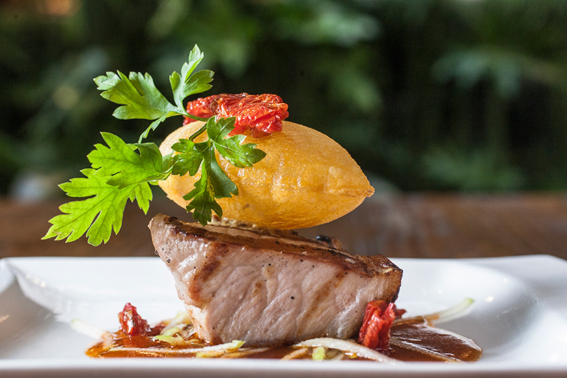 A picanha de porco vem rosada e com uma batata suflê sobre ela A picanha de porco vem rosada e com uma batata suflê sobre ela