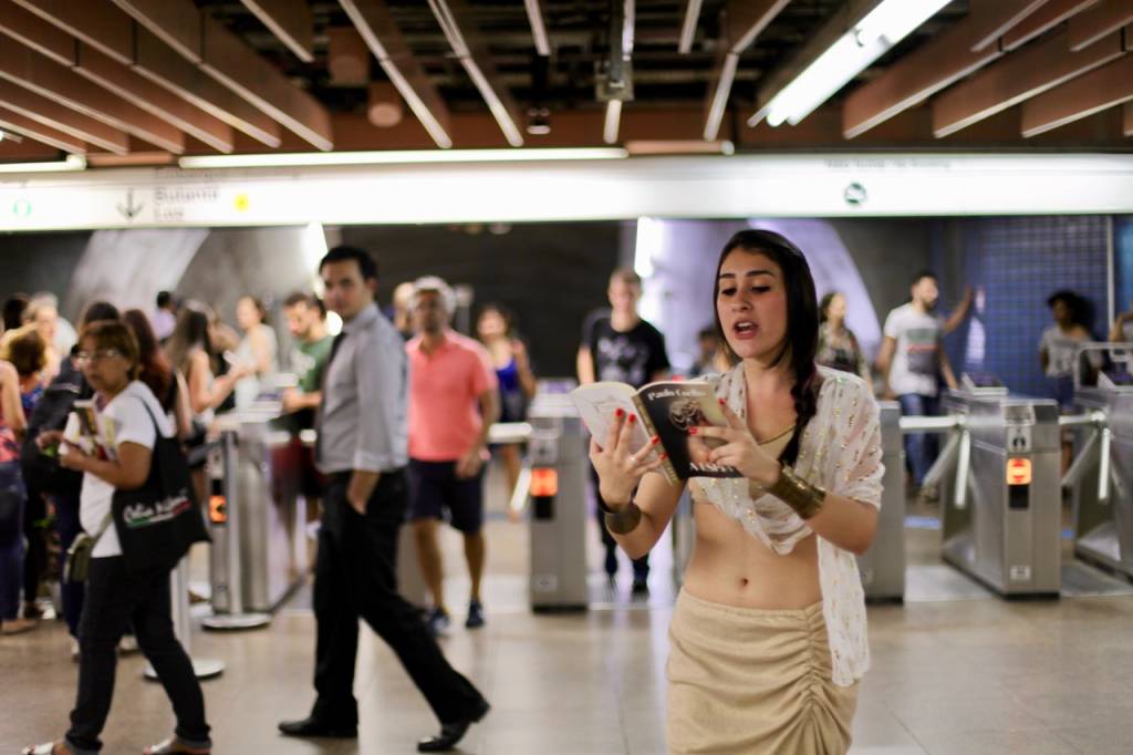 Mulher vestida de Mata Hari lê textos de Paulo Coelho no metrô