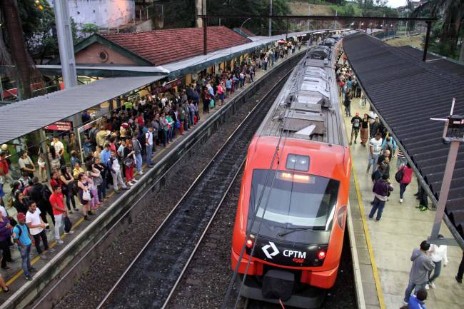 A imagem mostra uma estação da CPTM repleta de passageiros e um trem na plataforma