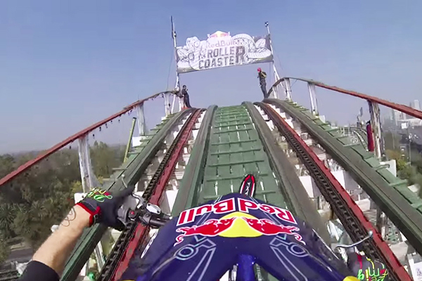 Aventureiro anda de moto nos trilhos de uma montanha-russa