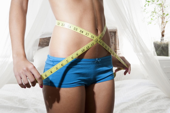 Woman Measuring Waist Using Tape Measure