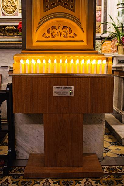 Velário eletrônico: permite que os fiéis façam suas orações ao depositar moedas. A “chama” fica acesa por, no mínimo, um minuto Velário eletrônico: permite que os fiéis façam suas orações ao depositar moedas. A “chama” fica acesa por, no mínimo, um minuto