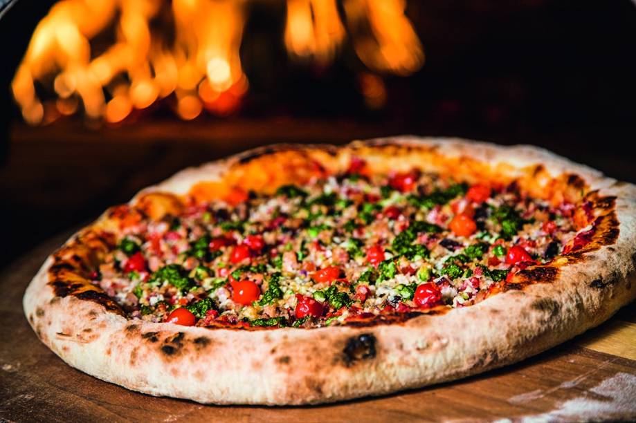 Pizza de carne de sol com manteiga de garrafa leva ainda queijos branco e de coalho, pimentas dedo-de-moça e cambuci, tomate e cebolinha