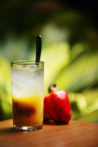 Drinque em copo longo com caju ao lado