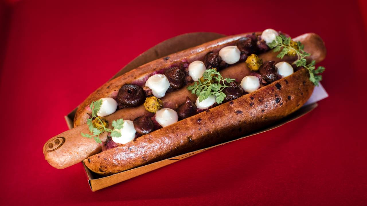 Cachorro-quente com círculos de molho e ervas