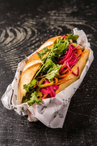 O lanche vietnamita traz na baguete frango levemente agridoce, cenoura, maionese de shoyu, coentro, pimenta jalapeño e picles O lanche vietnamita traz na baguete frango levemente agridoce, cenoura, maionese de shoyu, coentro, pimenta jalapeño e picles