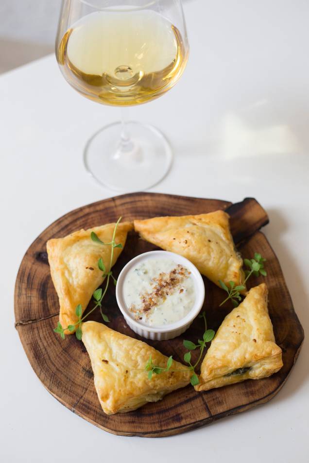 Espanacopita: torta de espinafre vem como um pastelzinho assado, triangular, recheado de queijo feta e crocante de azeitona junto de tzatziki, o pepino em iogurte e alho Espanacopita: torta de espinafre vem como um pastelzinho assado, triangular, recheado de queijo feta e crocante de azeitona junto de tzatziki, o pepino em iogurte e alho