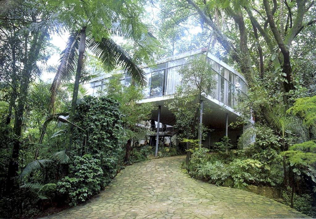 Casa de Vidro Imagem mostra casa com janelas de vidro em meio a matagal