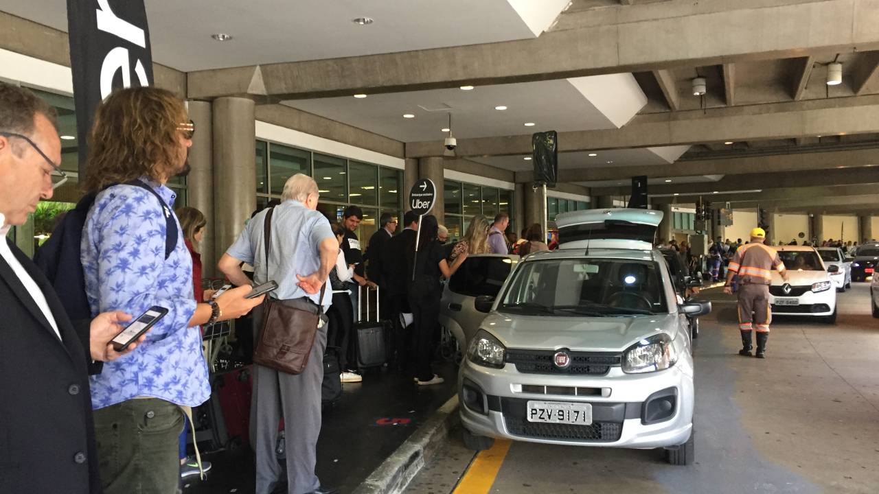 Imagem mostra passageiros aguardando embarque em carros na entrada do Aeroporto de Congonhas