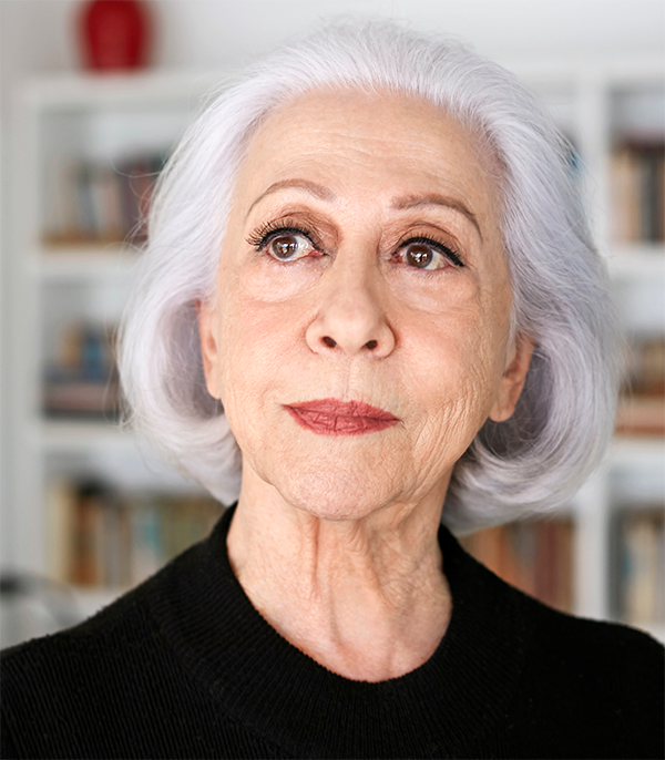 Imagem mostra Fernanda Montenegro com semblante sério, com estante de livros ao fundo