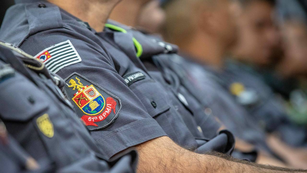 A imagem mostra uma foto de Policiais Militares enfileiradas, podendo ver apenas do ombro para baixo