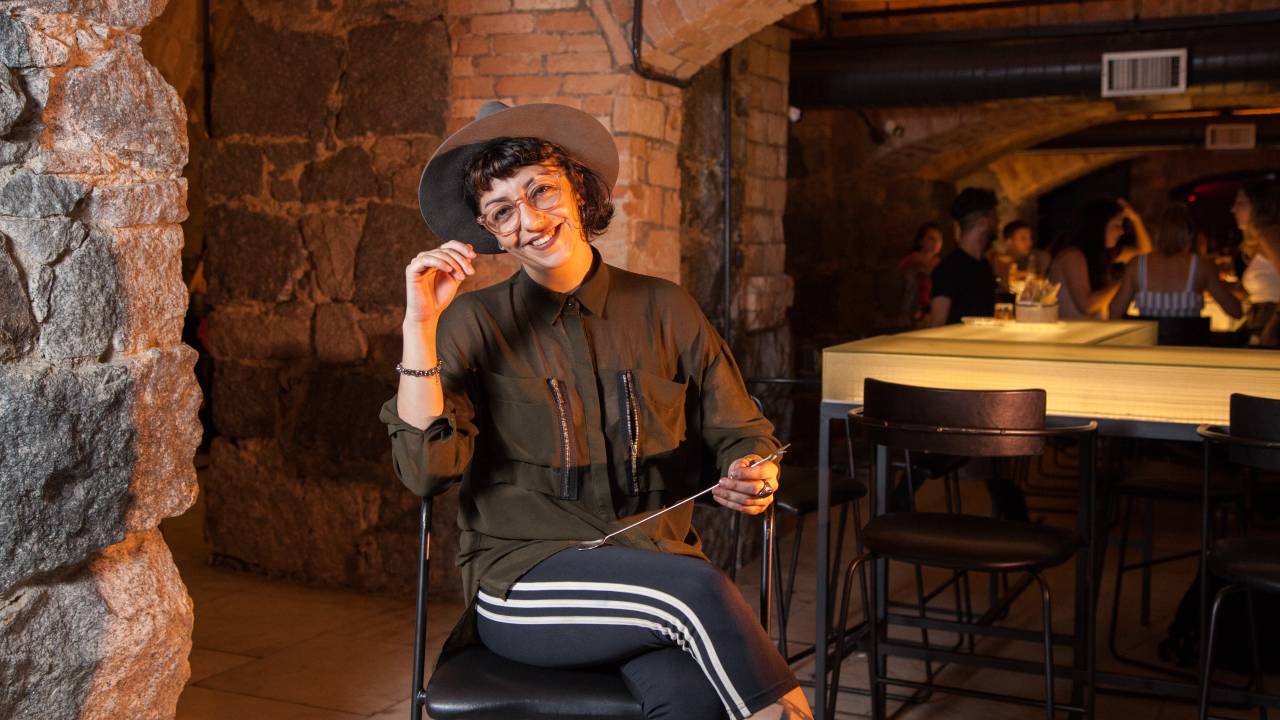 Mulher entada sobre uma banqueta em um bar mordendo uma colher