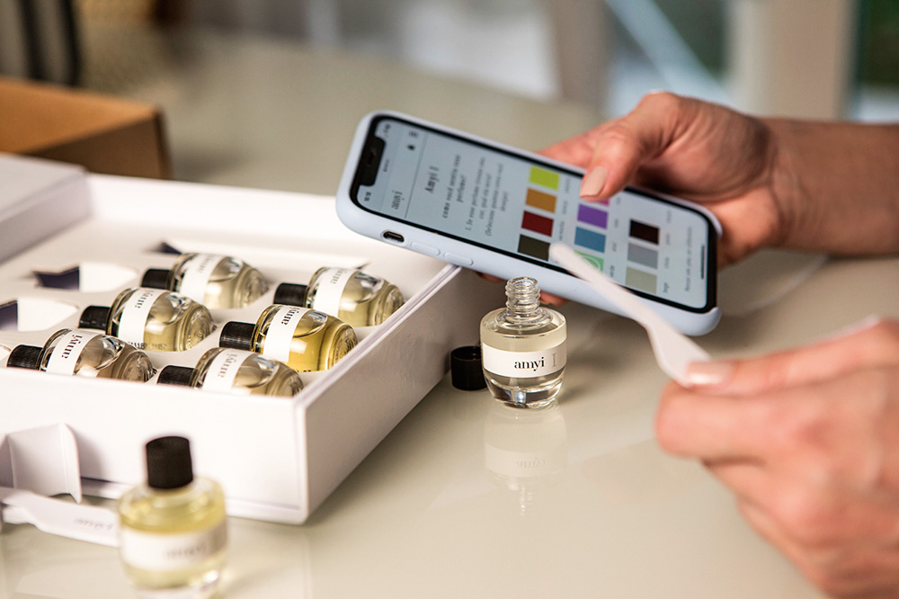 experiencia-amyi.JPG pessoa segurando o celular com o app da empresa aberto, para ranquear fragrãncias do kit