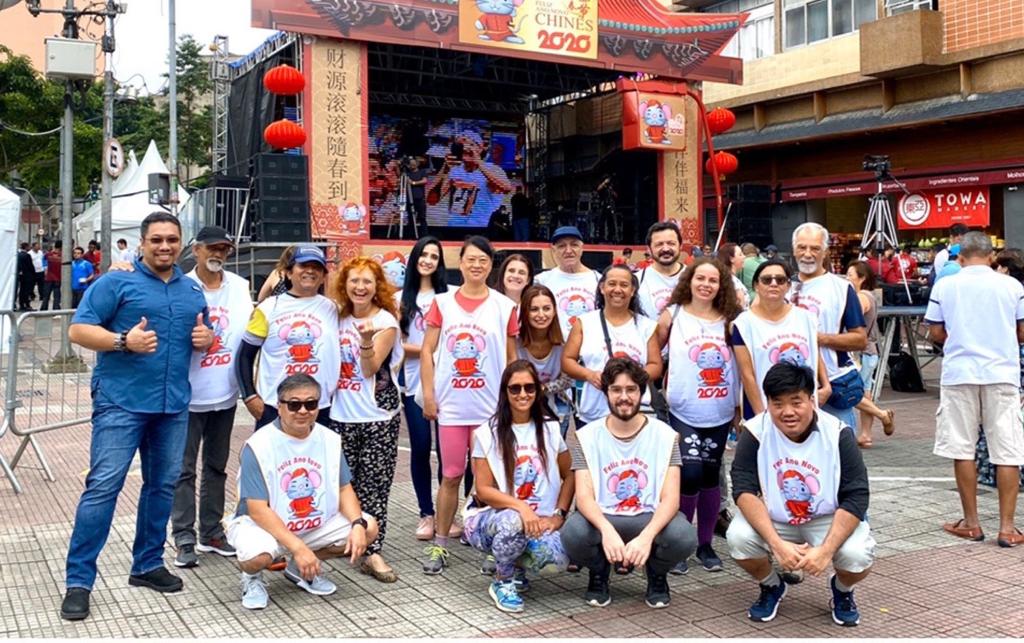 grupo-organizador-ano-novo-chinês-2020 grupo de pessoas de colete branco posando para a foto na frente de um palco
