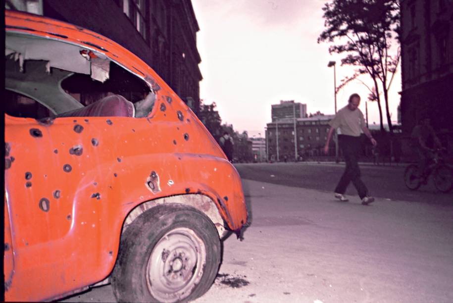 Marcas de bombardeios nas paredes e carro destruído abandonado na rua: cidade-ruína e ecos da violência Marcas de bombardeios nas paredes e carro destruído abandonado na rua: cidade-ruína e ecos da violência