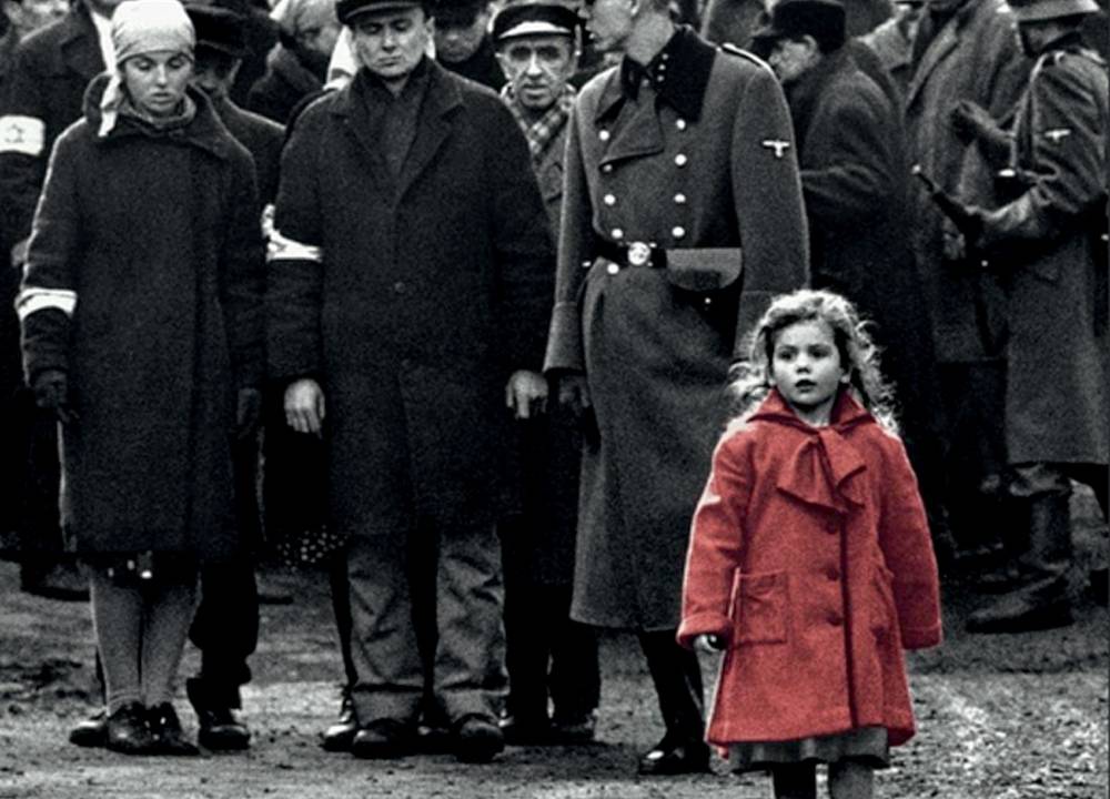 Em meio a oficiais de guerra em preto e branco, o corpo de uma menininha é a única parte colorida da foto, em vermelho, que caminha em frente a eles