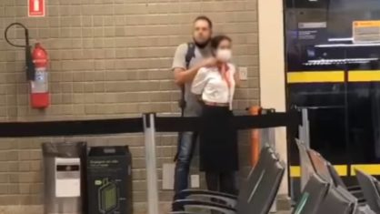 A imagem mostra um homem fazendo uma mulher refém com um objeto apontado para o pescoço dela