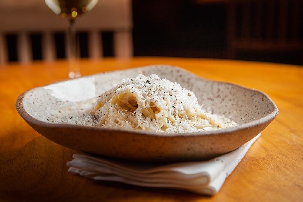 Espaguete cacio e pepe_2.jpg Espaguete cacio e pepe em um prato de cerâmica. Prato esta sobre uma toalinha dobrada branca.
