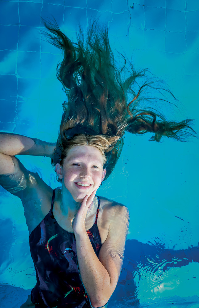 Olimpíadas-Tóquio-Atleta-Stephanie-Balduccini A imagem mostra Stephanie boiando em uma piscina. A câmera a vê de cima, e ela está sorrindo para a foto com todo o corpo submergido com exceção do rosto.