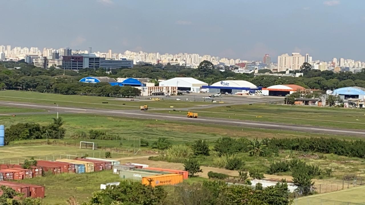 Imagem na altura de uma pessoa em p&eacute;. A dist&acirc;ncia, &eacute; poss&iacute;vel ver o helic&oacute;ptero tombado na pista do Campo de Marte.