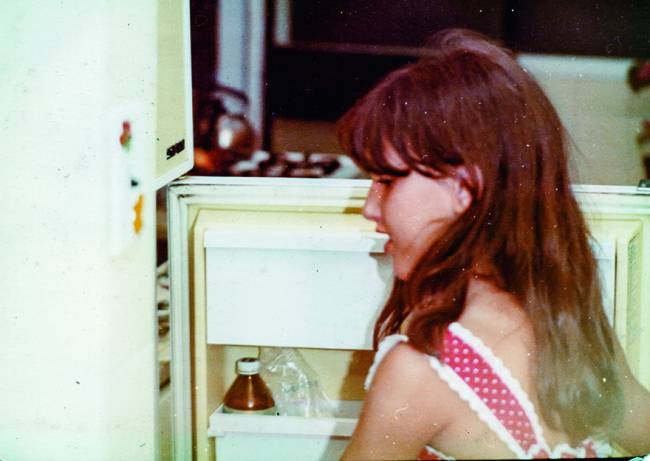 Menina abrindo porta da geladeira.