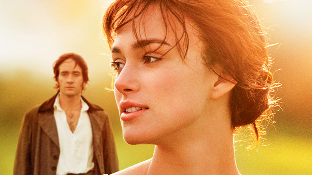 diadosnamorados4.jpg A imagem mostra Keira em um ambiente ensolarado olhando para o lado com Matthew ao fundo, um pouco desfocado