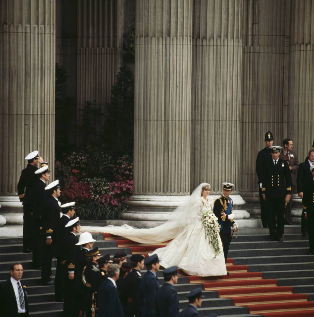 40-anos-casamento-principe-charles-princesa-diana-cerimonia-saida-igreja.jpg zoom out de charles e diana descendo as escadas da catedral na saída da cerimônia. soldados enfileirados na escada olhando para eles os acompanham