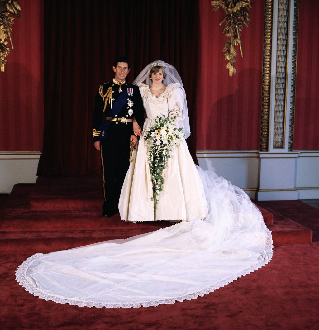 40-anos-casamento-principe-charles-princesa-diana-foto-casal.jpg Príncipe Charles e Princesa Diana posando para a foto oficial do casamento, feita pelo Lorde Lichfield no Buckingham Palace, após cerimônia na Catedral de São Paulo, em Londres. eles estão com as vestes do casamento em uma sala com tons majoritariamente vermelhos