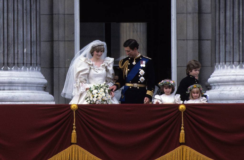 40-anos-casamento-principe-charles-princesa-diana-varanda-segurando-mao.jpg Príncipe Charles e Princesa Diana na varanda do Palácio de Buckingham com um de seus mensageiros, Lorde Nicholas Windsor, e duas de suas damas de honra, Catherine Cameron (à esq) e Clementine Hambro (à dir), após a cerimônia de casamento