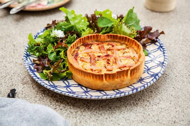 Torta de chucrute com parte superior de bacon trançado ao lado de salada de alface.