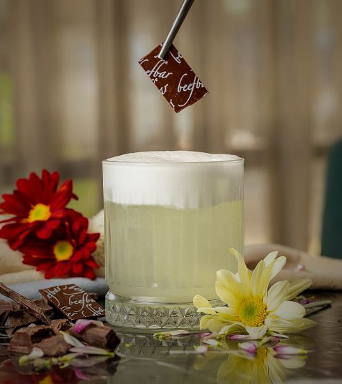 Drinque claro com espuma branca recebendo peda&ccedil;o de chocolate com pin&ccedil;a escrito Beefbar.