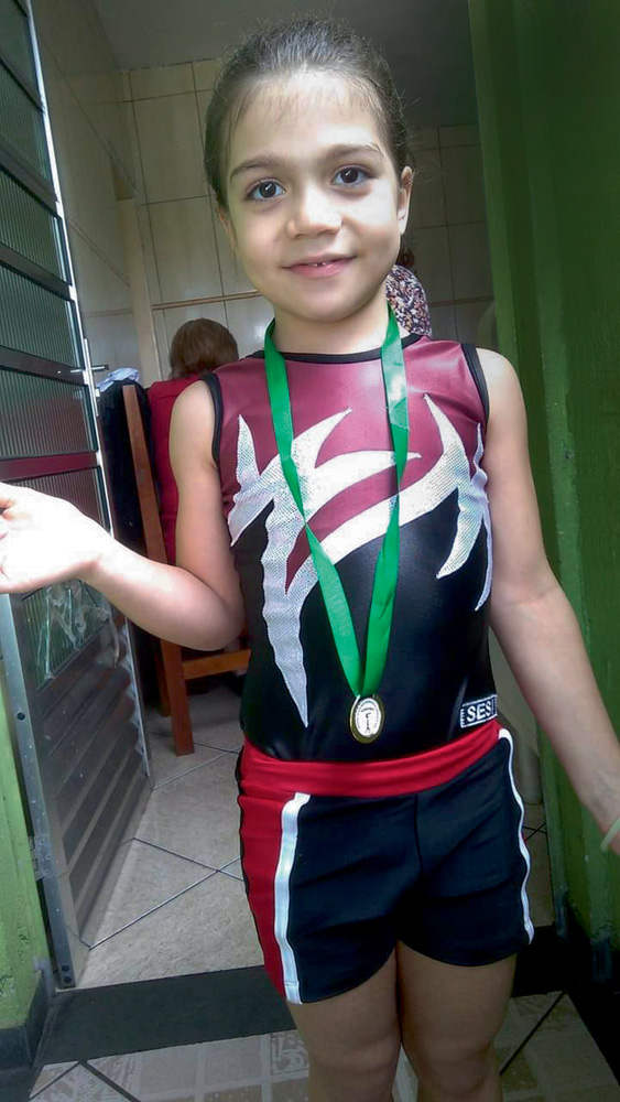 Rafaelly Neves A imagem mostra Rafaelly, em pé, com uma medalha e seu uniforme de ginasta.