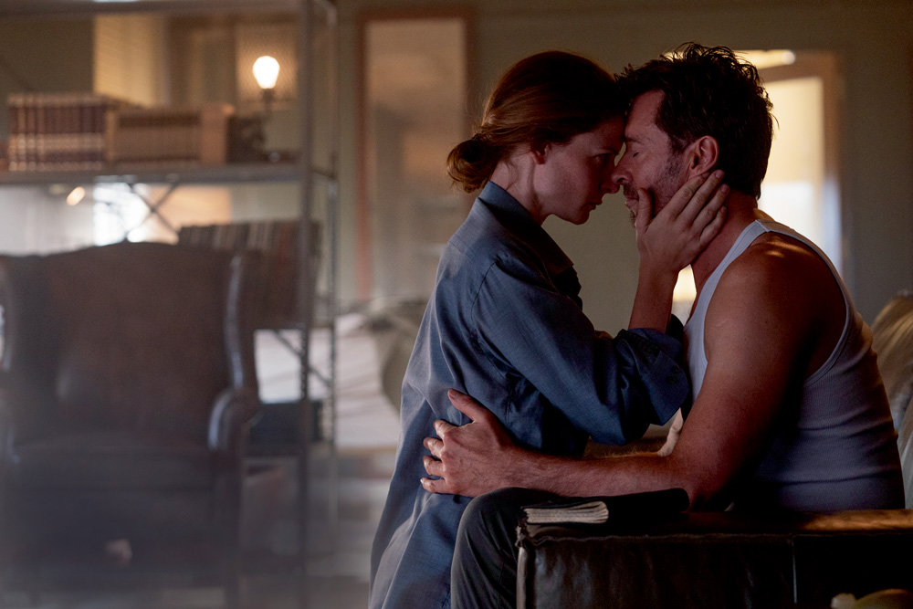 A imagem mostra Jackman e Ferguson abra&ccedil;ados, nariz a nariz, ele com os olhos fechados e ela de olho aberto.