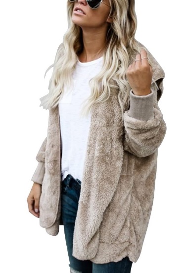 Mulher loira est&aacute; de lado vestindo casaco peludinho cinza