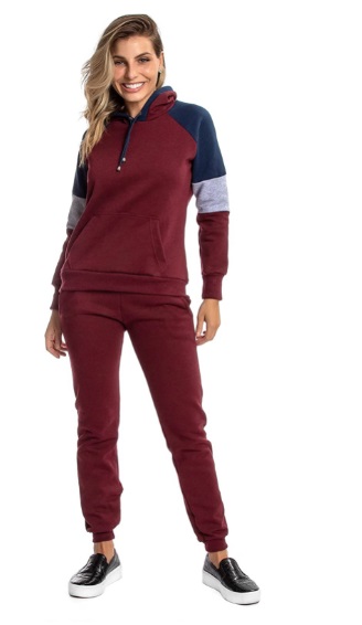 Mulher loira sorri para c&acirc;mera vestindo conjunto de cal&ccedil;a e moletom na cor vinho que combinam