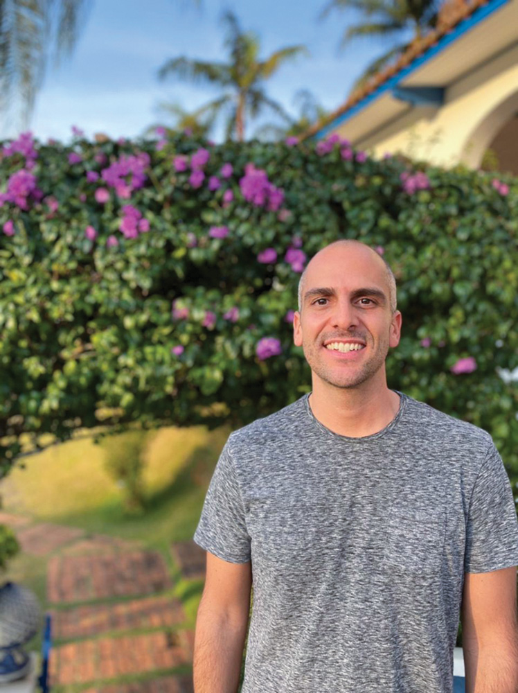 WhatsApp Image 2021-07-26 at 16.45.24.jpeg Homem careca e de blusa cinza posa sorrindo em frente a um jardim