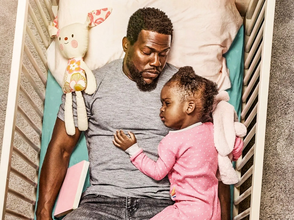 diados pais- netflix.jpg A imagem mostra Kevin deitado em um berço com um bebê apoiado em seu peitoral.