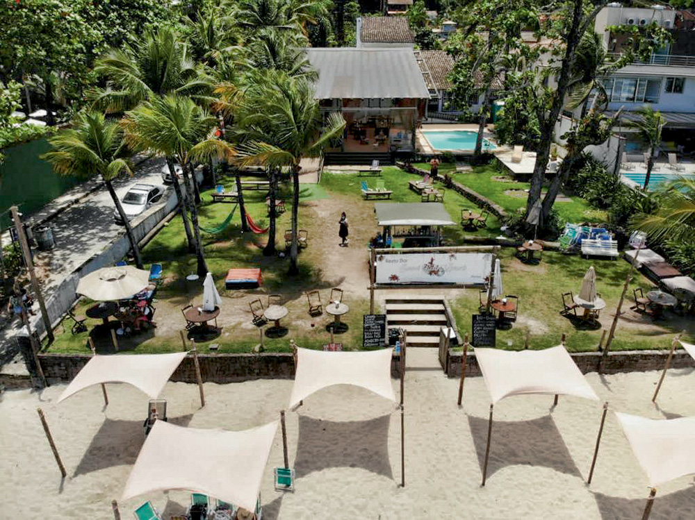 Sunset Bistrô Foto aérea mostra uma área de um bar restaurante à beira-mar. Tem quiosques, piscina e um grande gramado