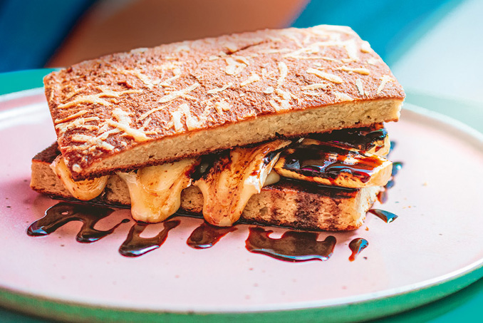 Sanduíche retangular de banana-da-terra com queijo brie com melaço escorrendo.