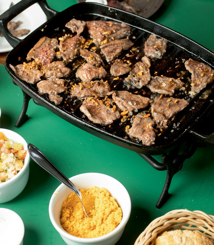 BARDOJUAREZlm62.jpg A imagem mostra uma bandeja com pedaços de picanha em cima de uma mesa com o pano verde.