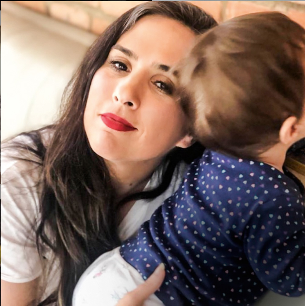 Tata Werneck com o filho A imagem mostra Tata Werneck segurando seu filho, que está de costas para a câmera, no colo. Ele é um bebê.