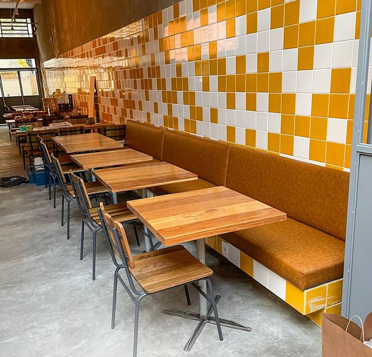 Ambiente do De*Segunda decorado por parede de azulejos brancos e amarelos