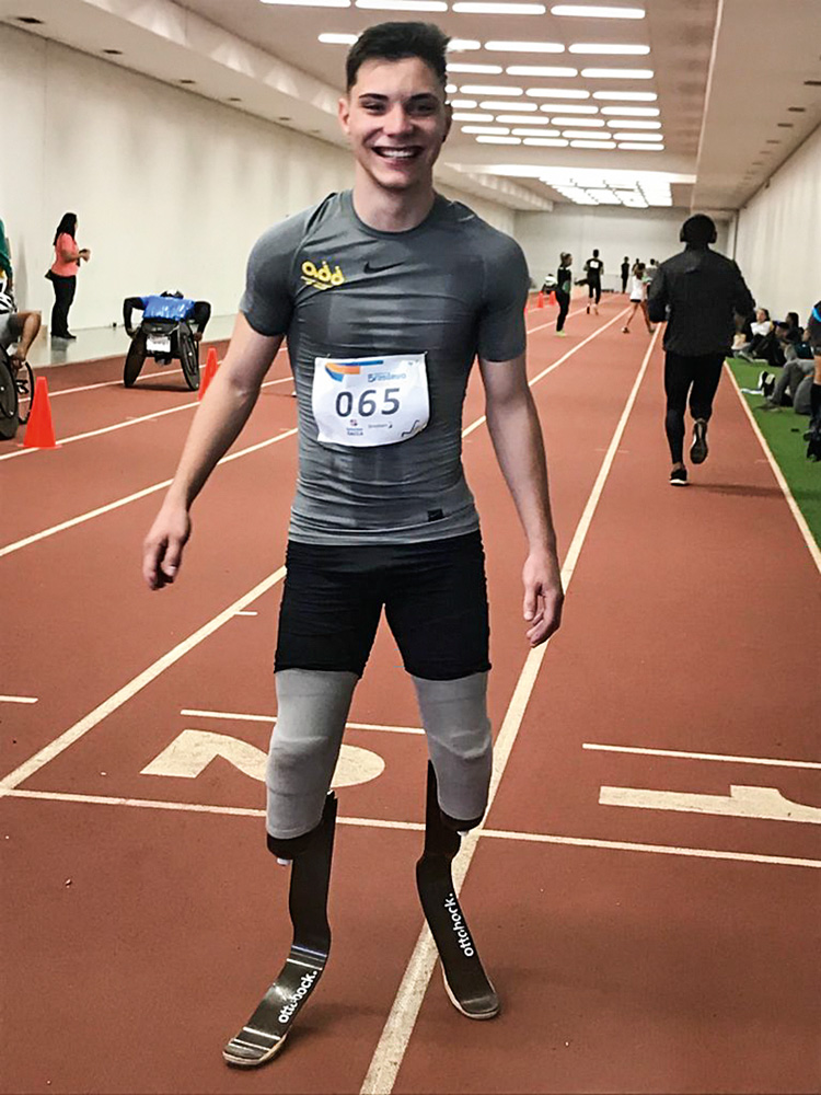 atletas-paralimpicos-amadores-experiências-pandemia-paralimpiadas-tóquio-Roger-Jacintho.jpg roger jacintho posando para a foto. ele está em uma pista de atletismo, com roupas esportivas. ele tem próteses nas duas pernas