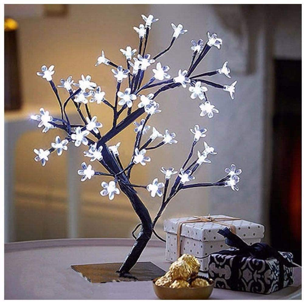 luminária Uma luminária branca acesa em formato de árvore de cerejeira. Está em uma mesinha de canto ao lado de outros adornos