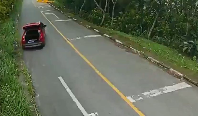 arrastão Guarujá vermelho A imagem mostra um carro vermelho, em uma estrada, com o porta-malas aberto e em movimento.