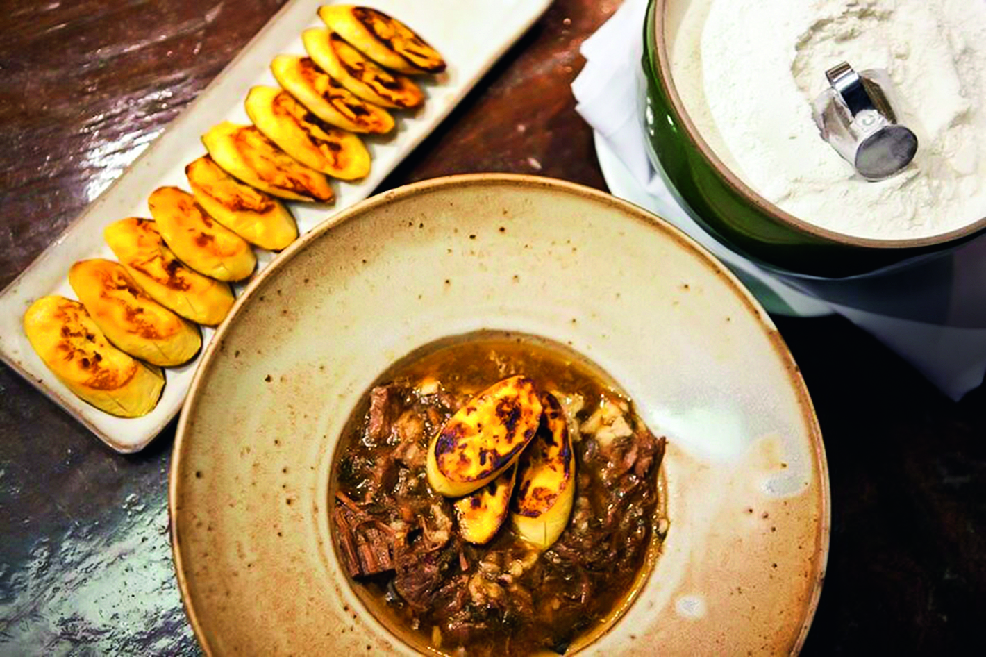 Prato fundo com barreada ao lado de travessa com peda&ccedil;os de banana tostados.